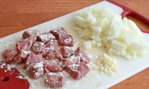 Wash the beef and cut into small cubes. Peel the onion and cut into pieces of medium size, chop the garlic. Sprinkle the meat with 1 tabl...