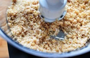 In a bowl of a food processor, mix almond flour, coconut chips and cookie crumbs with melted coconut oil and syrup.
