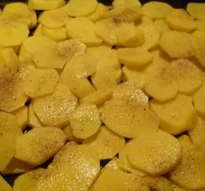 Peel the potatoes, cut them into thin slices and place them in a greased pan.