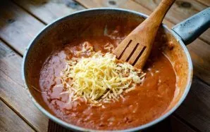 And we add coarsely grated cheese and garlic squeezed through a garlic press to the sauce thickened in a pan. Stir everything vigorously ...