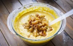 Add raisins and dried apricots cut into small pieces to the dough. Stir the dried fruit into the dough with a spatula.