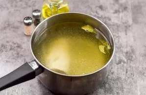 We put the meat in a saucepan, add water, put the bay leaf and boil the broth for 50 minutes over low heat.