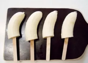 Wash and peel the bananas. Cut them in half and insert wooden sticks or wooden skewers from the cut side.