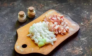Peel and wash the onion, cut into small cubes, and also chop the smoked bacon.