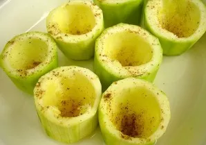 We take out the pulp from the zucchini columns to make cups. Salt them a little and pepper them.