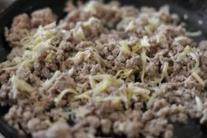 Fry the minced meat in oil, add salt and pepper. Grate half of the cheese and add to the cooled mince.