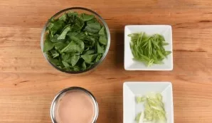 While the potatoes are frying, separately chop the green and white parts of the onion. Tear spinach. Mix the sauce with mayonnaise.