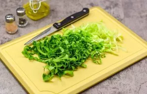 Disassemble the cabbage and rinse it well. Remove the coarse white part of the cabbage. Cut the green part into strips or as you wish.