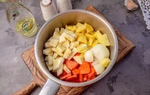 We put peeled and cut into small pieces onions, carrots, potatoes and zucchini in a saucepan.