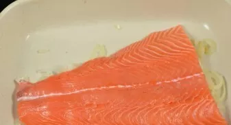 Then transfer the onions to a convenient baking sheet. Put a piece of salmon on top. Salt, pepper to taste and grease with mayonnaise.