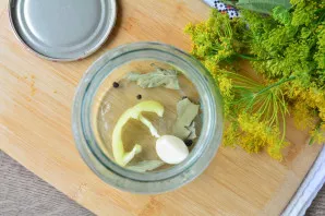 Add spices to the bottom of a clean, sterilized jar pepper peas, bay leaf, garlic cloves, add a small piece of sweet paprika for flavor.