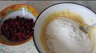Sift the flour with baking powder, gradually add to the dough, stirring. We wash the berries.