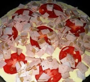 Pour the resulting mixture into a pan greased with vegetable oil. We put the filling on top - I have sausage and tomatoes, but you can ad...
