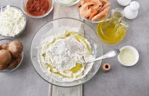 Mix flour, yeast and salt in a deep bowl. Add 2 tablespoons of olive oil and start kneading the dough, gradually adding warm water. The a...
