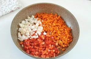 Cut carrots, bell pepper and onion into cubes. Put in a pan and pour oil.