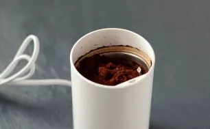 Grind coffee beans in a coffee grinder.