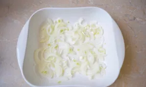 Grease the baking dish with a little vegetable oil. Cut the onion into half rings and spread evenly on the bottom.