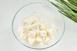 Prepare the dough. To do this, in a deep bowl, mix the flour, a pinch of salt, baking powder, sour cream and diced margarine.