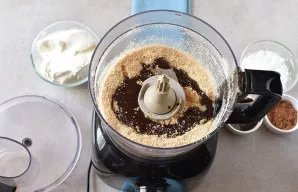 Grind the cookies into crumbs with a blender. Pour in the melted butter, add 2 tablespoons of chocolate syrup and mix again. The mixture ...