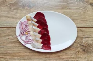 Cut the herring fillet into slices 0.5 cm thick. Peel the onion and cut into thin half rings, peel the beets, cut in half and cut into sl...