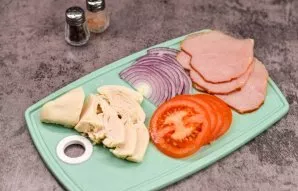 Cut the chicken fillet into slices, cut the ham into slices, cut the onion into half rings, cut the tomatoes into circles.