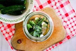 Add spices garlic cloves, peppercorns, bay leaf and herbs to the bottom of sterilized jars. Lay out a few dried dill sprigs and a crush...