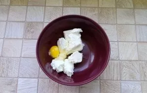 Prepare the filling for the cake. Put the cottage cheese and egg in a bowl.