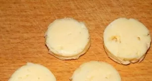 From the cheese you need to cut round pieces, which will serve as hats of snowmen.