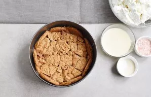 Line a baking tray with baking paper. Place the broken cookies on the bottom and sides of the dish.