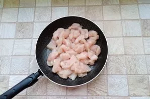 Wash the chicken fillet and cut into small pieces. Put in a pan with sunflower oil.
