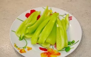 We clean the seeds from the sweet pepper, wash it and cut it lengthwise into strips.