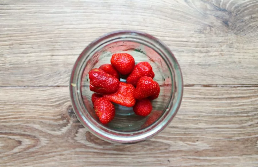 Remove the stems from the strawberries, put the berries in a jar.