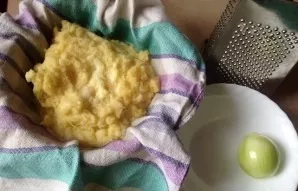 Then we cover the colander with a linen towel, put the colander in a bowl and add the chopped potatoes. Squeeze the potatoes well, but no...