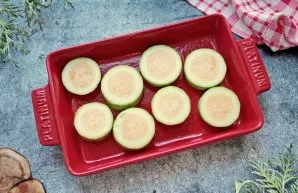 Cut off the ends of the zucchini and cut into circles 1-1.5 centimeters thick. Grease the baking dish with vegetable oil and put the zucc...