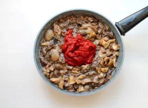 Pour vegetable oil into the pan and heat over medium heat. Add the mushrooms and fry for 10 minutes. Add tomato paste to the mushrooms.
