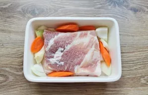 Peel the vegetables and cut them into large pieces. Place them on the bottom of the baking dish. Place the pork on top of them, skin side...