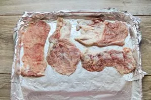 Cut the pork into portions, knock it out, rub it with salt and pepper. Line the baking sheet with foil and lay out the chopped pieces of ...