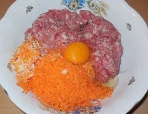 Add carrots and garlic to minced meat. Beat the egg right there. Season with salt and pepper.