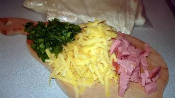Grate the cheese on a coarse grater, finely cut the sausage into cubes, chop the greens finely.