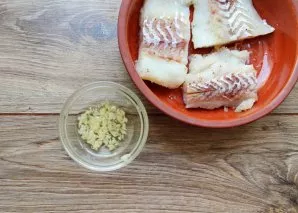 Chop the garlic and mix with the remaining oil. Coat the cod fillet completely with garlic oil, pour the rest into the mold.