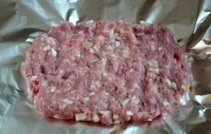 Add onion to the mince, squeeze a clove of garlic, salt and pepper to taste. Place the mince on a sheet of foil and form a rectangle abou...