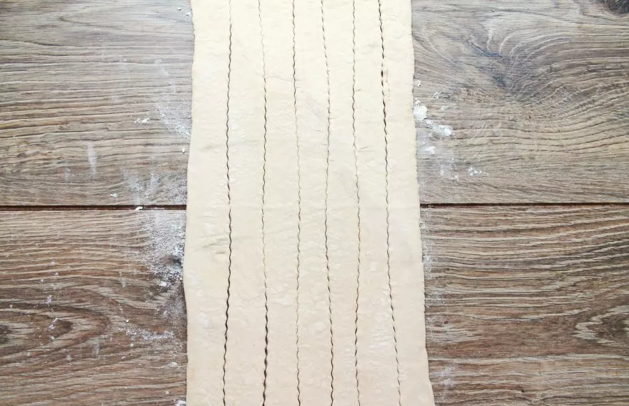 Lightly sprinkle the table with flour and roll out the dough in one direction into a long rectangle, cut into strips.