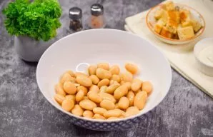 Open a can of canned beans and drain the liquid. Transfer the beans to a salad bowl.