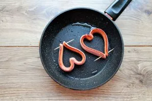 Pour vegetable oil into the pan and heat over medium heat. Put sausages-hearts and fry on one side for 1-2 minutes, turn over.