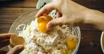 Put the squeezed zucchini in a bowl, add half the cheese, add flour, herbs, soda and salt, beat the eggs and mix well.