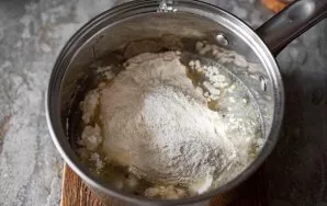 Remove the pot with the boiling oil mixture from the stove and immediately add all the flour.