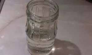 We take a small clean jar with a small neck. We pour water into it.
