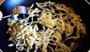 Next, thinly chopped garlic is placed in the pan. While stirring, fry for another 1 minute.