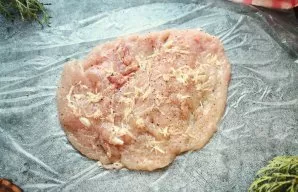 Cut the chicken breast with a knife and knock it into a layer. Salt, pepper and grease with crushed garlic.