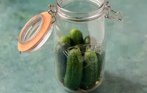 Tightly put the cucumbers halfway into the jar. Then add the second part of spices and garlic. Stack the remaining cucumbers.
